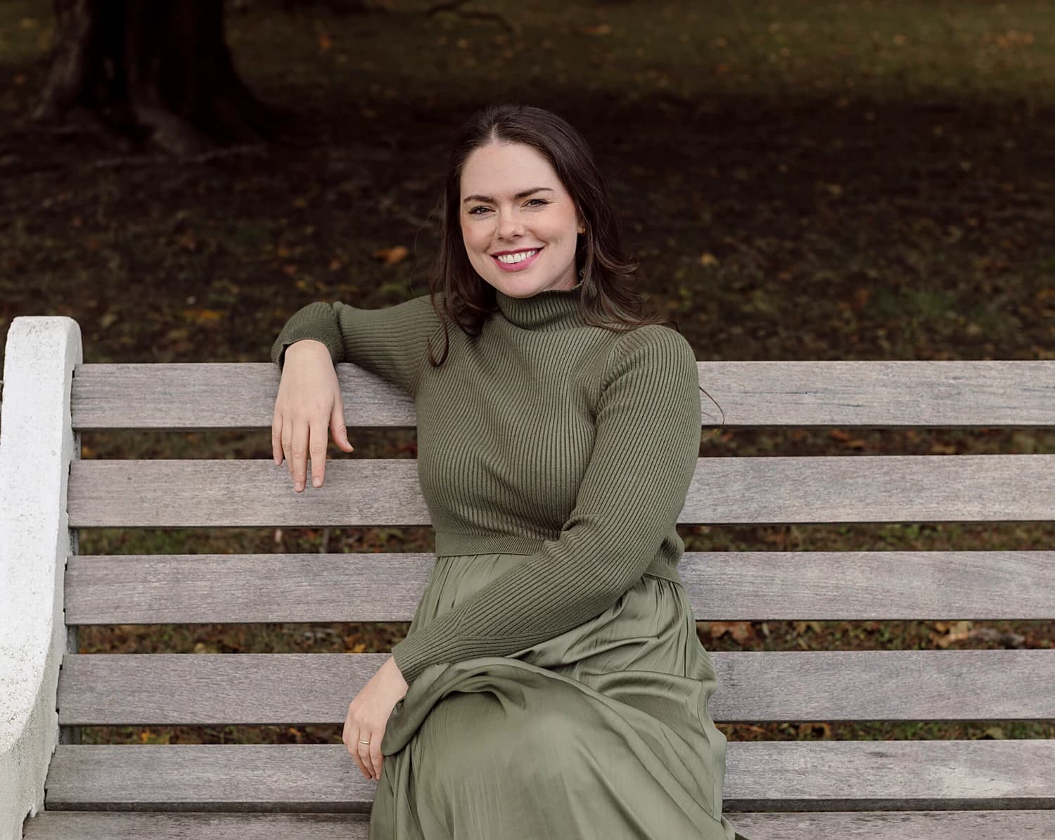 Emily Horstman, Registered Dietitian, seated on a park bench in an olive knit and skirt